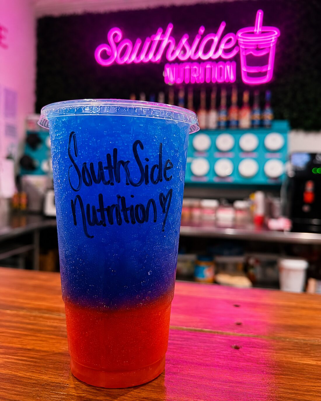 A tall two-tone loaded tea under the pink neon logo